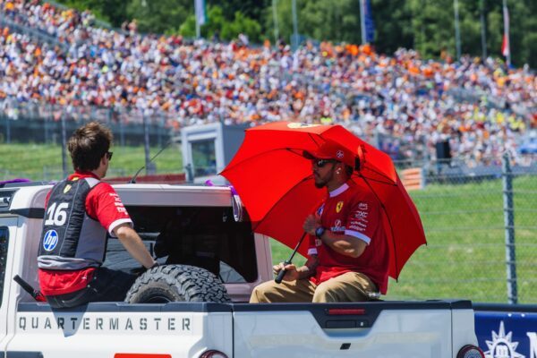 Die Ferrari-Fahrer Charles Leclerc (links) und Lewis Hamilton schützen sich im Vorjahr mit einem Schirm und einer Kühlweste vor der Hitze. Auch am Wochenende wird es in Spielberg heiß. (Archivbild)