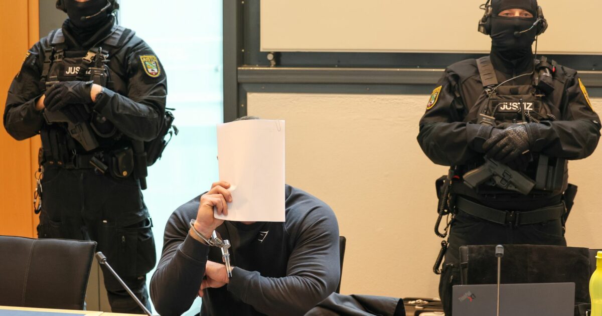 Der Angeklagte sitzt im Gerichtssaal des Landgerichts Magdeburg zwischen zwei Justizbeamten.