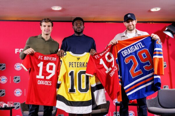 Fußball und Eishockey als Partner: Die deutschen Eishockeystars John-Jason Peterka (l) und Leon Draisaitl (r) mit dem kanadischen Bayern-Profi Alphonso Davies.