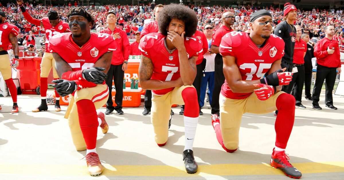Colin Kaepernick (Mitte) kniend bei der Nationalhymne. Er bekam Unterstützung einiger Mitspieler